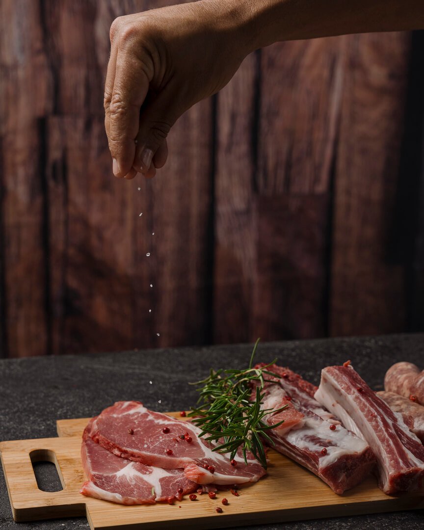Mano che sala fettine di maiale su tagliere Carlo Poma