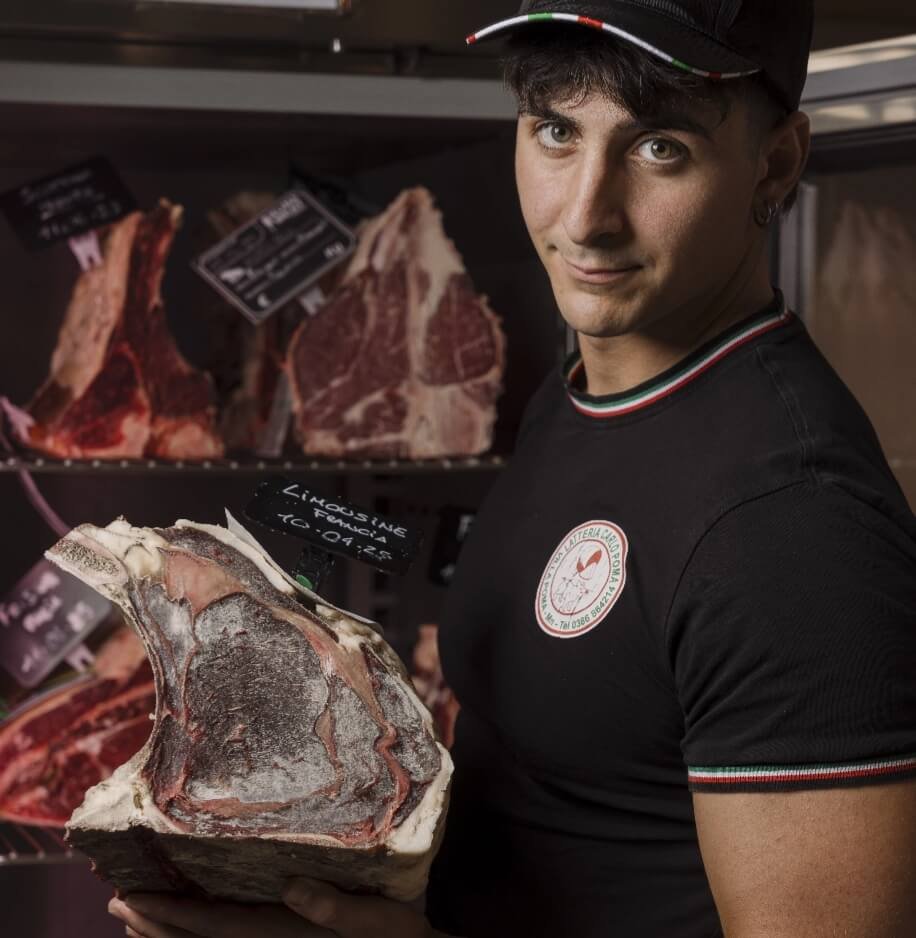 Macellaio mostra taglio di carne frollata in macelleria artigianale