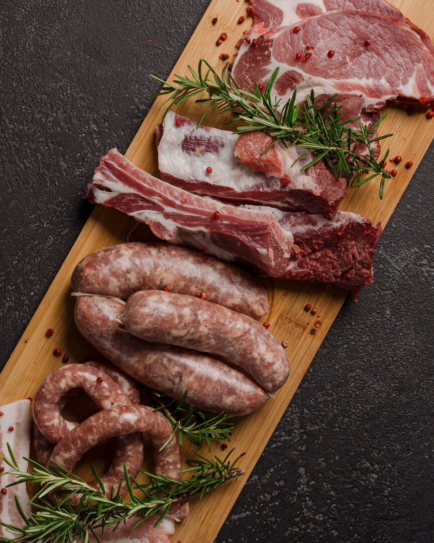 Salsicce fresche e costine con rosmarino su tagliere Carlo Poma