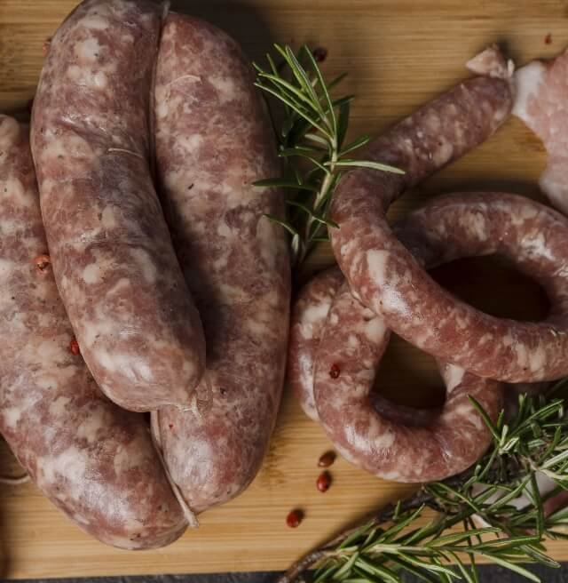 Salsicce fresche artigianali su tagliere con rosmarino