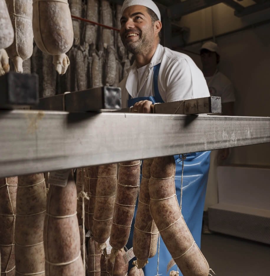 Addetto macelleria che controlla salumi appesi in stagionatura