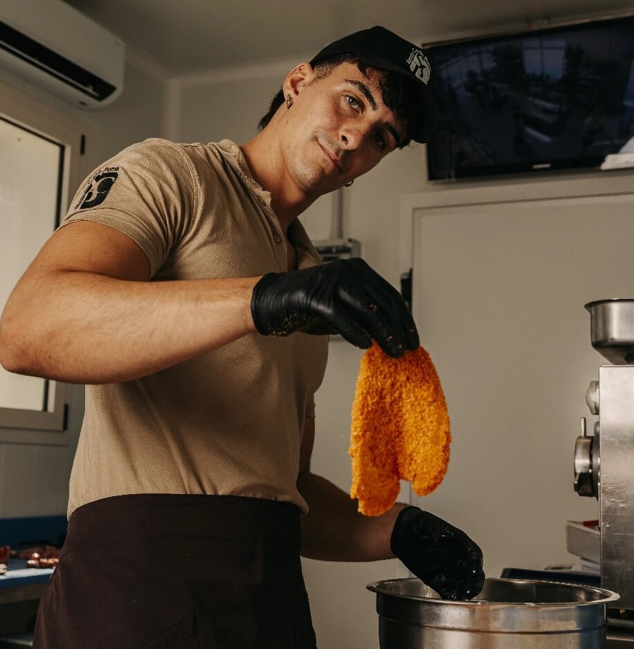 Addetto prepara cotoletta impanata nel laboratorio Carlo Poma